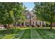 A traditional brick home with manicured front lawn and mature trees offers charm and curb appeal at 9735 Devonshire Dr, Huntersville, NC 28078