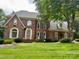 Charming two-story brick home featuring a lush front lawn and mature trees providing shade at 10500 Kilmory Ter, Charlotte, NC 28210