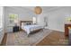 Airy bedroom with white walls, wood floors, patterned rug, and a view to the bathroom at 15628 Waterfront Dr, Huntersville, NC 28078
