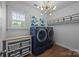 Bright laundry room featuring blue front load machines, storage, and stylish light fixture at 15628 Waterfront Dr, Huntersville, NC 28078