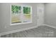 Bright living room with gray wood-look flooring, a large window, and a freshly painted white door at 2732 Mayfair Ave, Charlotte, NC 28208