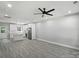 Open-concept living space with gray floors, leading to a kitchen featuring stainless steel appliances and island at 2732 Mayfair Ave, Charlotte, NC 28208