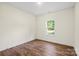 Empty bedroom with hardwood floors, a window overlooking the yard, and neutral-painted walls at 5328 Oaktree Dr, Gastonia, NC 28052