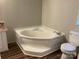 Bathroom featuring a corner tub, toilet, and wood-look vinyl flooring at 6218 Old Pageland Marshville Rd, Marshville, NC 28103