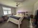 Comfortable bedroom with a queen-size bed, neutral decor, a ceiling fan, and a window overlooking the backyard at 707 Regency Dr, Charlotte, NC 28211