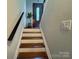 Staircase with hardwood treads, white risers, and a dark handrail leading to the front door at 707 Regency Dr, Charlotte, NC 28211