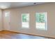 Bright, empty living room with hardwood floors, two large windows, and a white door at 11017 Warfield Ave # 4, Huntersville, NC 28078