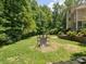 View of a well-maintained backyard with green lawn, mature trees, professional landscaping, and lacrosse goal at 2103 Lytton Ln, Matthews, NC 28104