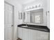 White bathroom with black granite countertop and large mirror with vanity lighting at 2656 Polo Club Blvd, Matthews, NC 28105