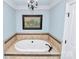 Modern bathroom with soaking tub, tile surround, and stylish chandelier at 8500 Peyton Randolph Dr, Charlotte, NC 28277