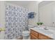 Bright bathroom with stylish floral shower curtain, wood vanity, and a plant at 9136 Four Mile Creek Rd, Charlotte, NC 28277