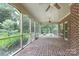 Spacious outdoor screened-in porch with brick floor and brick walls, views of wooded backyard, and two ceiling fans at 1503 Jack White Dr, Rock Hill, SC 29732