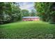 Expansive backyard with lush greenery, featuring a charming red brick home and deck at 1538 Hilltop Dr, Shelby, NC 28150