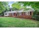 Beautiful brick home with white trim, black shutters, and lush green grass and mature trees at 1538 Hilltop Dr, Shelby, NC 28150