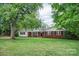 Charming brick home with inviting entryway, black shutters, and beautiful, mature trees at 1538 Hilltop Dr, Shelby, NC 28150
