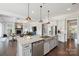 Open-concept kitchen featuring a large island, stainless steel appliances, and seamless flow into the living room with fireplace at 19012 Beecher Commons Dr, Huntersville, NC 28078