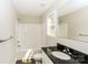 The well-lit bathroom features a black granite counter, a window, and a shower with a bathtub, creating a clean and functional space at 671 Sylvan Sw St, Concord, NC 28025