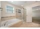 Bathroom featuring a soaking tub, glass-enclosed shower, and tiled floors at 7362 Waterwheel Sw St, Concord, NC 28025