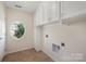 Bright laundry room with storage cabinets, tile floor, and a unique oval window at 7362 Waterwheel Sw St, Concord, NC 28025