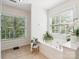 Bright bathroom featuring a soaking tub and large windows overlooking the greenery outside at 13930 Daltrey Ln, Charlotte, NC 28277