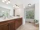 Well-lit bathroom with double vanity, wood cabinets, and a view of the outdoors at 13930 Daltrey Ln, Charlotte, NC 28277