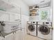 Bright laundry room featuring a washer, dryer, laundry sink, and shelving for organized storage at 13930 Daltrey Ln, Charlotte, NC 28277