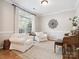 Bright living room with white chairs, piano, large window and a decorative wall art piece at 13930 Daltrey Ln, Charlotte, NC 28277