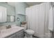 Bathroom with a sink, toilet and shower with a white curtain, and a large mirror at 17406 Tuscany Ln, Cornelius, NC 28031