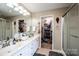 Bathroom featuring dual sinks, white cabinetry, walk-in shower, walk-in closet and decorative mirror in neutral tones at 2635 Mahogany Ln, Hickory, NC 28602
