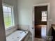 Bathroom with soaking tub, tiled surround, and natural light from window at 3837 1St Street Nw Ln, Hickory, NC 28601