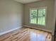 A simple bedroom with hardwood floors and a window providing natural light and a view of a well maintained lawn at 3837 1St Street Nw Ln, Hickory, NC 28601