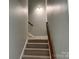 Carpeted stairs with wooden handrail leading upwards, bathed in gentle light, promising comfort and accessibility at 3837 1St Street Nw Ln, Hickory, NC 28601
