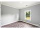 Well-lit bedroom with fresh gray paint, wood flooring, and a view of the landscaped yard at 405 E Broad St, Salisbury, NC 28144