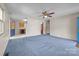 Inviting living room featuring blue carpet, a ceiling fan, and views into the kitchen at 416 Park Ave, Granite Quarry, NC 28072