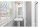 A clean powder room with a pedestal sink, window, and neutral decor at 9921 Oaklawn Nw Blvd, Huntersville, NC 28078