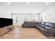 A well-lit and spacious living room boasts wood flooring, a leather sectional sofa, and large windows at 9921 Oaklawn Nw Blvd, Huntersville, NC 28078