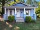 Charming light blue home featuring a cozy front porch with white columns and trimmed windows with a landscaped yard at 116 Honeywood Ave, Charlotte, NC 28216