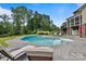 A large pool, lounge chairs, jacuzzi, and a view of the home's exterior and wooded landscape at 330 Waters Rd, Salisbury, NC 28146