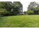 A large, grassy backyard features mature trees and a storage shed at 6421 Hidden Forest Dr, Charlotte, NC 28213