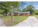 Charming brick home featuring a well-manicured lawn, mature trees, a concrete driveway, and colorful landscaping at 6421 Hidden Forest Dr, Charlotte, NC 28213