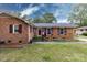 Charming brick home featuring a well-manicured lawn, colorful landscaping, and complementary colored shutters and front door at 6421 Hidden Forest Dr, Charlotte, NC 28213