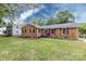 Charming brick home featuring a well-manicured lawn, colorful landscaping, and complementary colored shutters and front door at 6421 Hidden Forest Dr, Charlotte, NC 28213