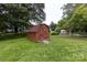 A wooden storage shed stands on a grassy lawn with mature trees at 6421 Hidden Forest Dr, Charlotte, NC 28213