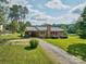 Charming brick home with a metal roof, a red door, and a spacious front yard at 7753 Caswell Rd, Stanley, NC 28164