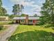 Charming brick home with a red front door, metal roof, inviting driveway, and lush lawn at 7753 Caswell Rd, Stanley, NC 28164