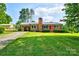 Charming brick home with a red door, manicured bushes, and a lush green lawn at 7753 Caswell Rd, Stanley, NC 28164