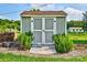 A well-maintained storage shed with double doors is nestled in a beautiful yard with greenery and firewood at 7753 Caswell Rd, Stanley, NC 28164