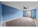 A carpeted bedroom with blue walls, a ceiling fan, and natural light entering through a window, offering a calm, relaxing space at 2680 Heavens Ct, Fort Mill, SC 29715