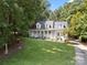 Expansive front lawn leading to a charming white home with dormer windows nestled among mature trees on a sunny day at 480 Robinson Rd, Mooresville, NC 28117