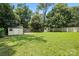 Wide shot of the large, grassy backyard featuring a swing set and two storage sheds at 5126 Unaka Ave, Charlotte, NC 28205